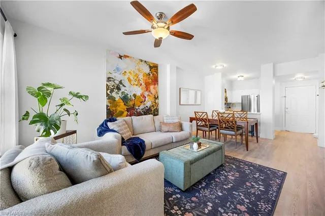 a living room with furniture kitchen view and a large window