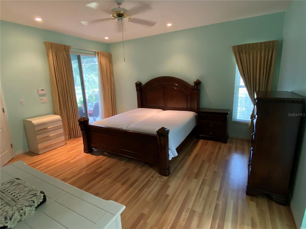 4202 Hammersmith Drive Clermont, FL 34711 - Photo 18 of 73 a bedroom with a bed lamps and wooden floor