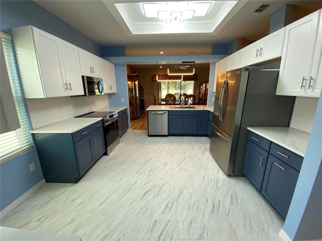 4202 Hammersmith Drive Clermont, FL 34711 - Photo 42 of 73 a kitchen with stainless steel appliances a refrigerator a sink a stove a microwave and wooden cabinets