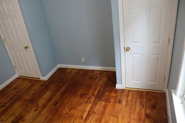 an empty room with wooden floor and closet