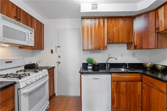 a kitchen with stainless steel appliances granite countertop wooden cabinets a stove a sink and a window