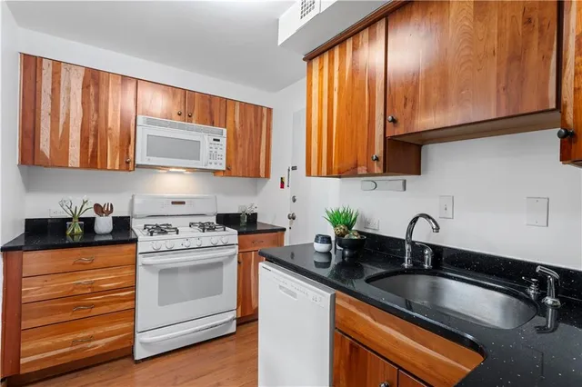 a kitchen with granite countertop cabinets stainless steel appliances a sink and a window