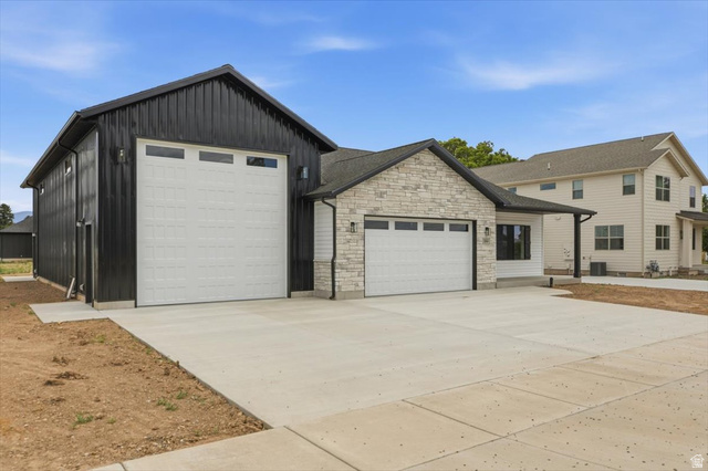 164 North 400 East Preston, ID 83263 - Photo 21 of 21 Modern residence featuring a large attached accessory building with a wide garage door, a two-car garage with a stone facade, and a concrete driveway
