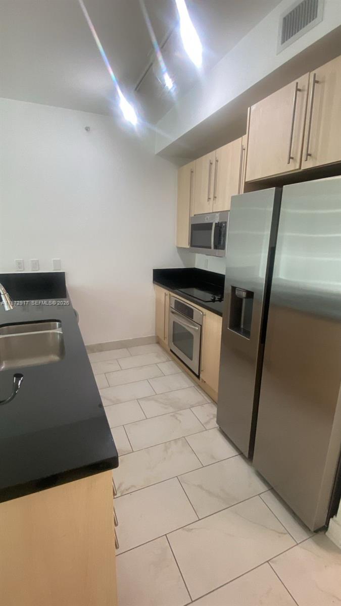 1111 Southwest 1st Avenue, Unit 2016N Miami, FL 33130 - Photo 6 of 20 a kitchen with granite countertop a stove a sink and a refrigerator
