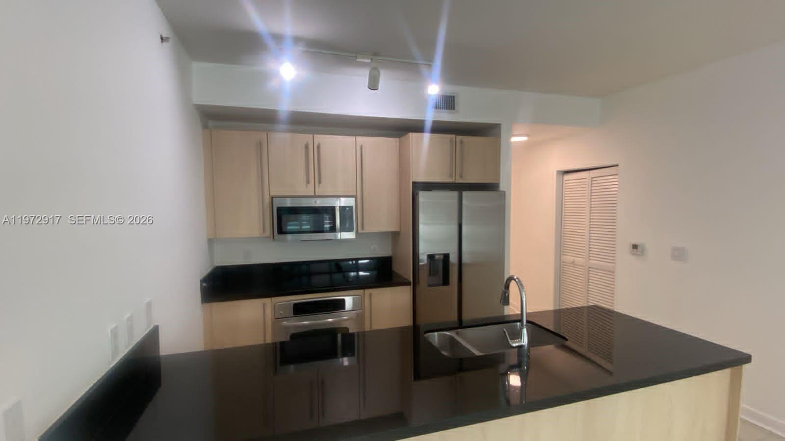 1111 Southwest 1st Avenue, Unit 2016N Miami, FL 33130 - Photo 8 of 20 a kitchen with granite countertop a refrigerator a stove and a sink