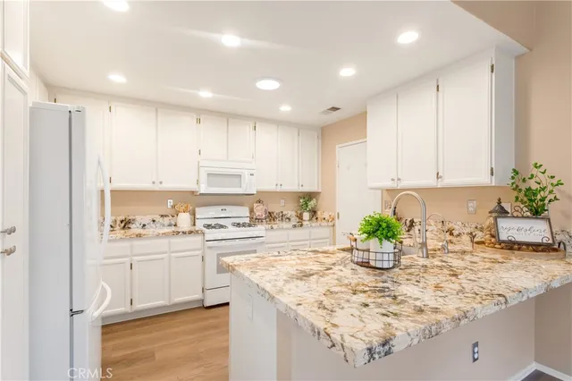 a kitchen with kitchen island granite countertop a sink a stove a dining table and chairs