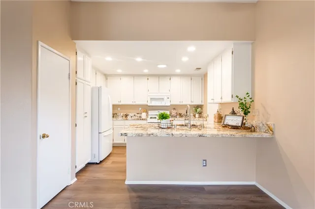 a kitchen with stainless steel appliances granite countertop a white cabinets and a hard wood floor
