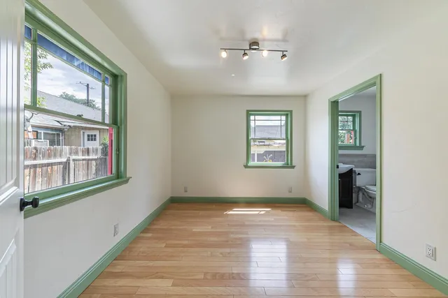 a view of an empty room with a window and wooden floor