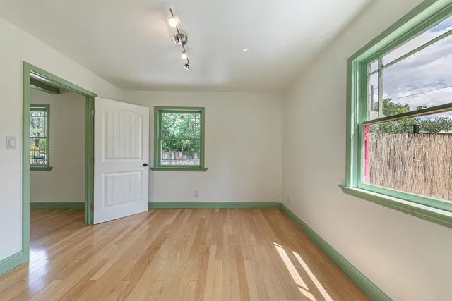 an empty room with wooden floor and windows