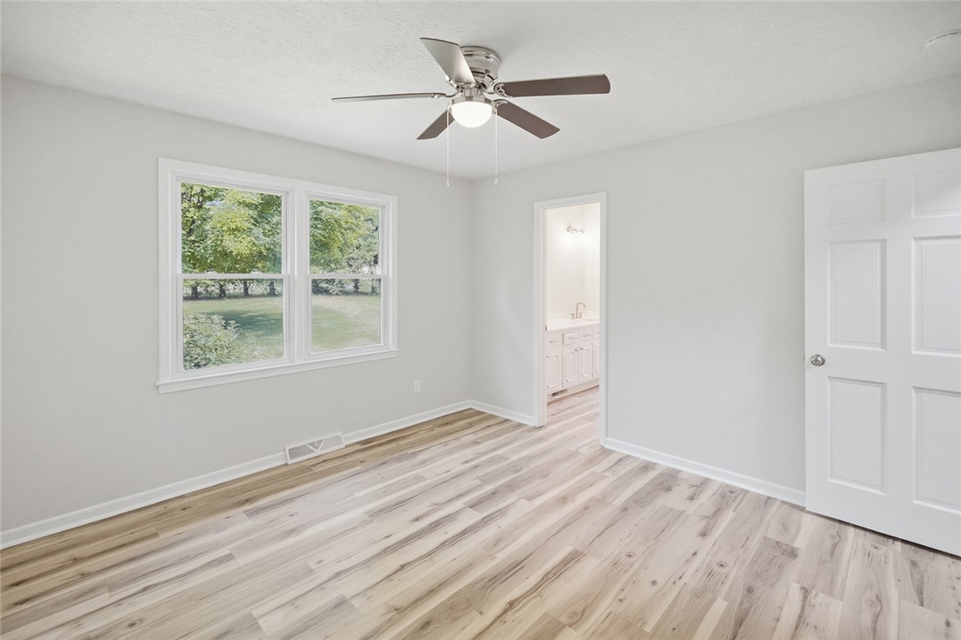 902 Cherokee Road Pelzer, SC 29669 - Photo 14 of 38 A tranquil bedroom with wood-look flooring and a ceiling fan, offering a serene escape with views of nature.