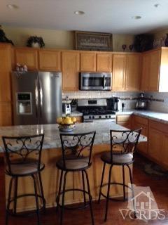 1889 Ribera Drive Oxnard, CA 93030 - Photo 4 of 22 a kitchen with stainless steel appliances a dining table chairs microwave and sink
