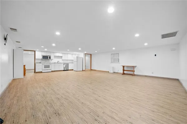 a white kitchen with granite countertop a stove top oven a sink dishwasher a refrigerator and cabinets with wooden floor