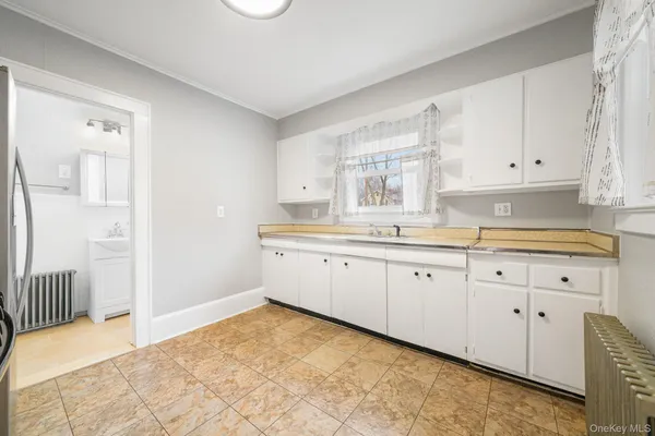 a large white kitchen with granite countertop a sink white cabinets and a window