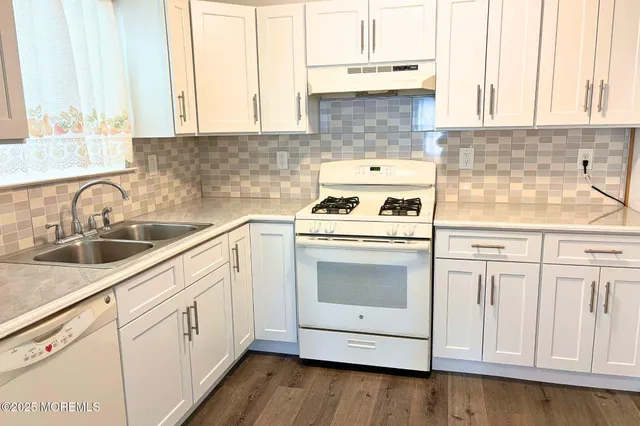 a kitchen with white cabinets sink and appliances