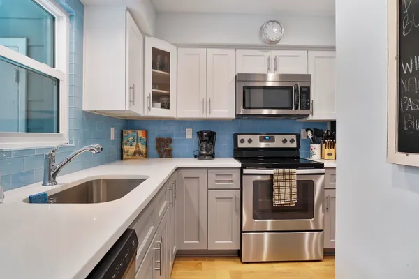 a kitchen with stainless steel appliances granite countertop a sink a stove and microwave