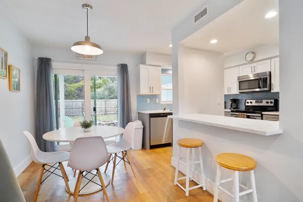 a large white kitchen with stainless steel appliances granite countertop a sink a stove a dining table and chairs