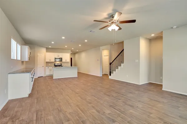 a view of a livingroom with a ceiling fan kitchen appliances and a window