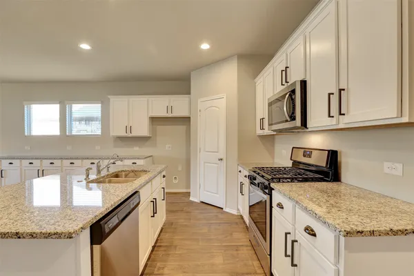 a kitchen with stainless steel appliances granite countertop a stove a sink and a refrigerator