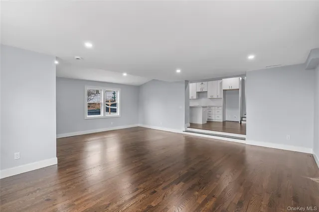 a view of an empty room with wooden floor and windows