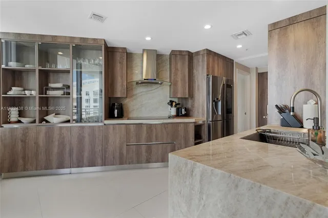 a kitchen with stainless steel appliances kitchen island granite countertop a refrigerator and a sink