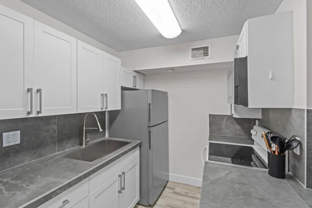 a kitchen with stainless steel appliances granite countertop a sink a refrigerator and a granite counter tops