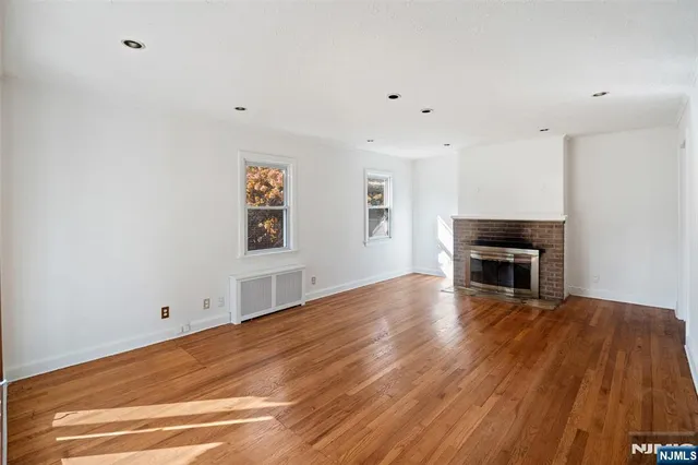 a view of empty room with wooden floor and fireplace