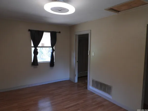 an empty room with wooden floor cabinet and windows