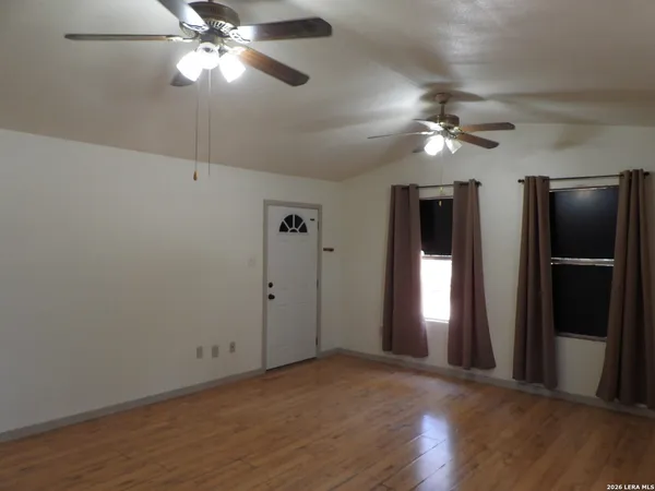 a view of empty room with wooden floor and fan
