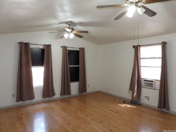 a view of empty room with wooden floor and fan