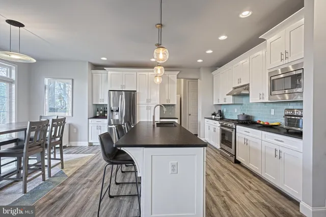 a kitchen with granite countertop a table chairs stove microwave and cabinets