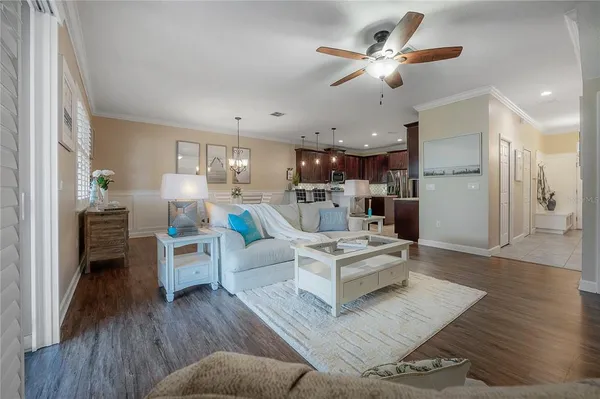 a living room with furniture kitchen view and a chandelier
