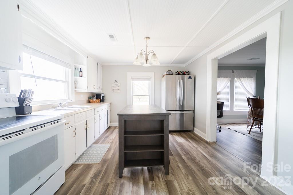 5204 Fish Road Marshville, NC 28103 - Photo 12 of 20 a open kitchen with a refrigerator a sink dishwasher a dining table and chairs with wooden floor