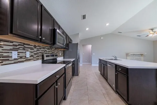 a kitchen with stainless steel appliances granite countertop a sink a stove and a wooden floors
