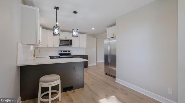 a kitchen with stainless steel appliances granite countertop a sink a stove a refrigerator and white cabinets