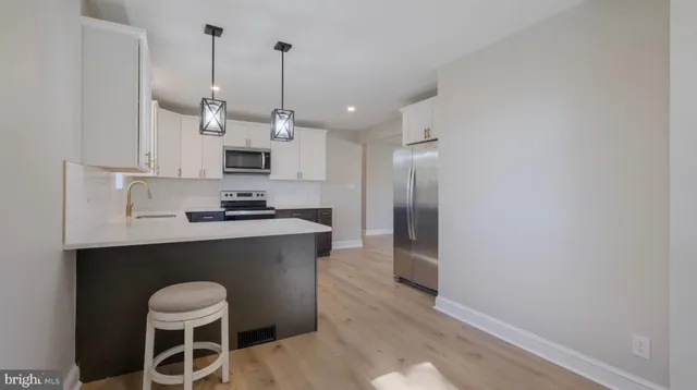 a kitchen with stainless steel appliances granite countertop a sink a stove a refrigerator and white cabinets