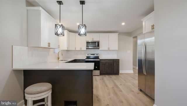 a kitchen with stainless steel appliances granite countertop a sink a stove a refrigerator and island with wooden floor