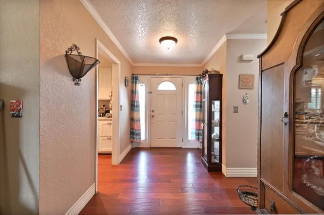 a kitchen with stainless steel appliances kitchen island granite countertop a refrigerator a sink dishwasher a stove and white cabinets with wooden floor