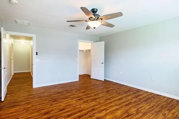 an empty room with wooden floor and ceiling fan