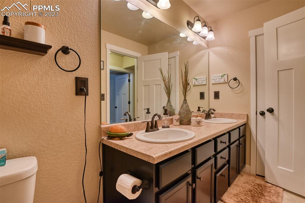 9785 Terrain Road Fountain, CO 80817 - Photo 31 of 40 a bathroom with a granite countertop sink a toilet and a mirror