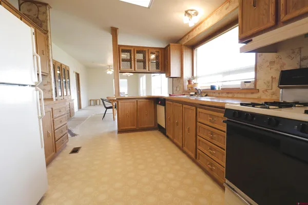 a kitchen with stainless steel appliances granite countertop a stove top oven a sink dishwasher a dining table and chairs with wooden floor