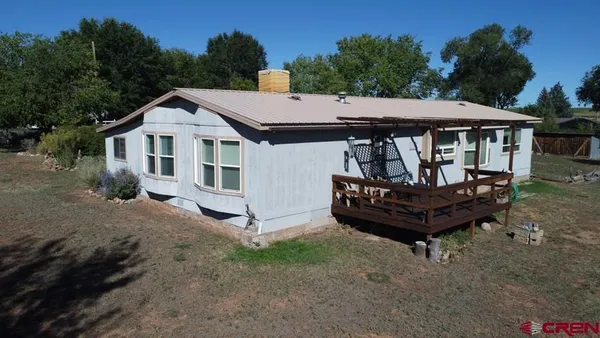 a view of a house with a wooden deck and a backyard