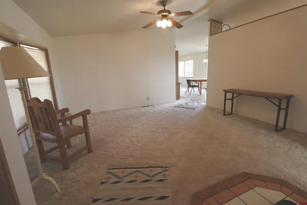 a view of an empty room with a chandelier fan and a rug