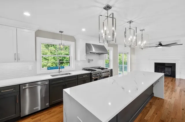 a kitchen with stainless steel appliances a sink a stove a chimney a center island and a window