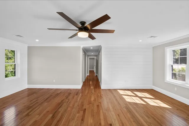 a view of empty room with wooden floor and fan