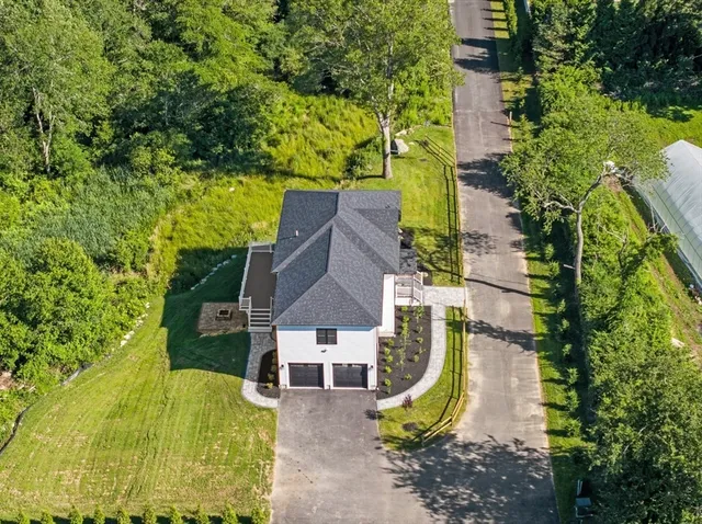 an aerial view of a house with swimming pool and large trees