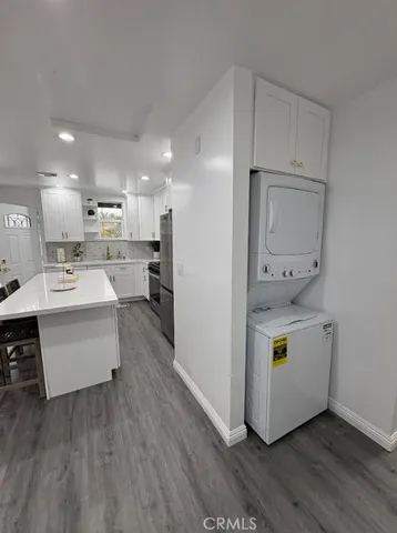 a large white kitchen with kitchen island a sink a stove a refrigerator and white cabinets with wooden floor