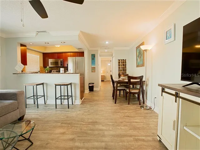 a dining hall with stainless steel appliances kitchen island granite countertop a table chairs and a refrigerator