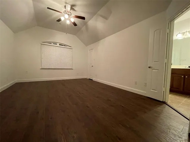 an empty room with wooden floor ceiling fan and windows
