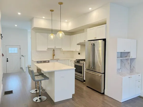 a kitchen with stainless steel appliances a refrigerator a sink a stove a dining table and chairs