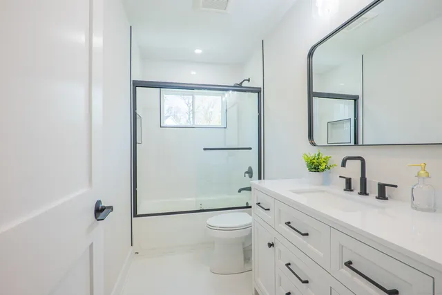 a bathroom with a granite countertop sink a toilet and shower